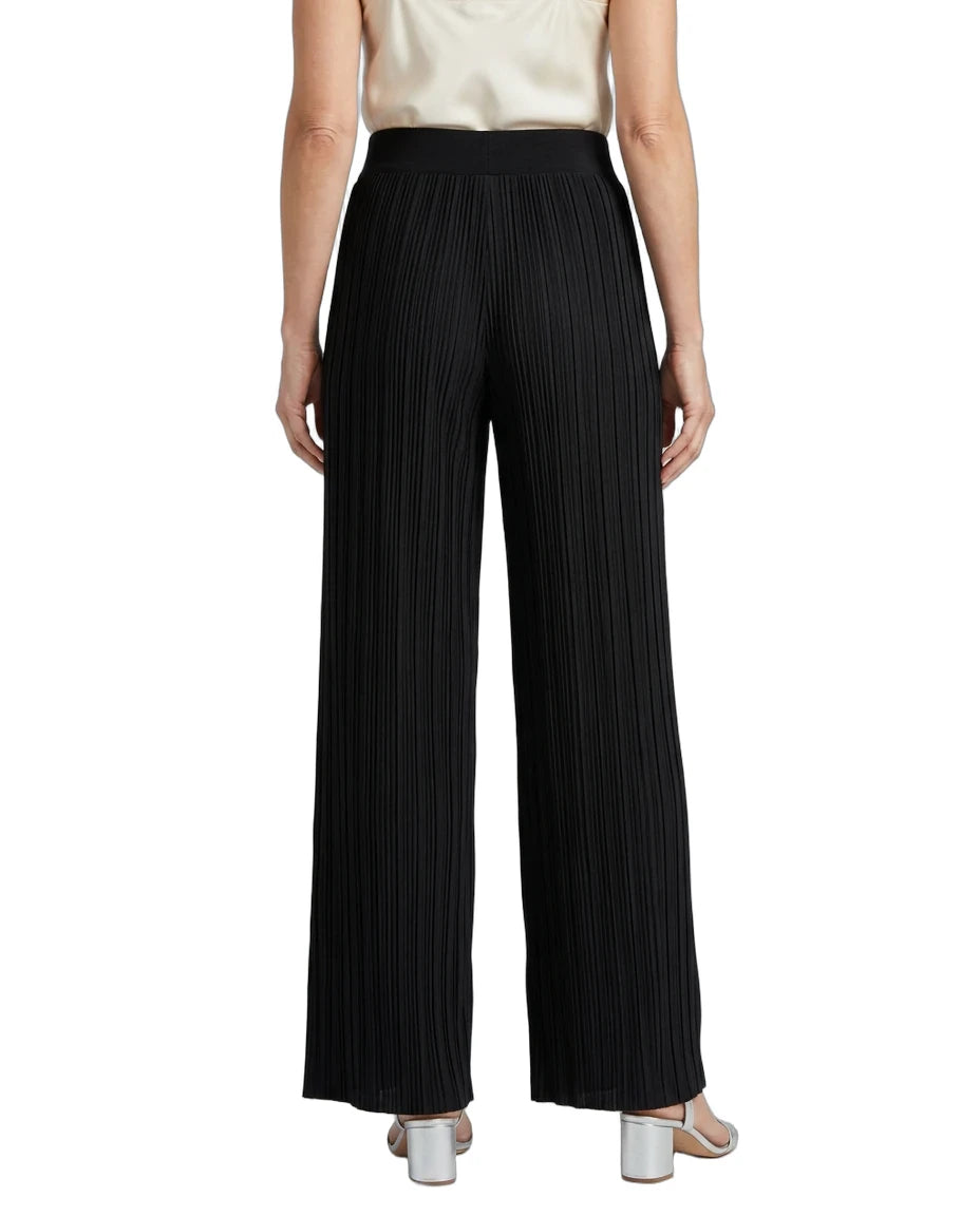 Black pleated wide-leg trousers shown from the back on a model, paired with a cream top and metallic silver heels, against a plain white background.