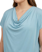 Light blue cowl-neck top worn by a person on a white background
