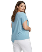 Woman wearing a light blue top and white pants on a white background