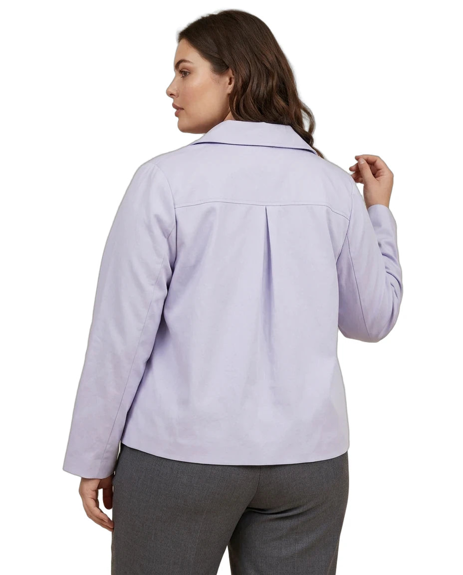 A woman shown from the back wearing a light lavender long-sleeve collared shirt and gray pants against a plain white background.