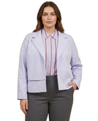 A woman modeling a light lavender cropped blazer over a pink striped button-down shirt and gray trousers, shot against a plain white background.