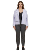 A woman modeling a light lavender blazer over a black top and dark gray trousers, standing against a plain white background.