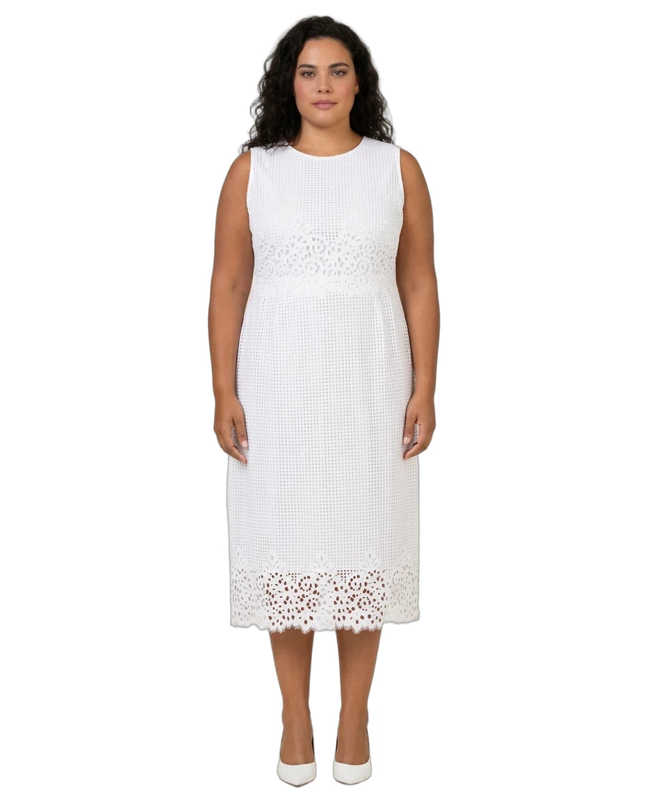 A woman modeling a sleeveless white midi dress with textured knit fabric and eyelet lace trim at the waist and hem, paired with white pointed-toe heels, against a plain white background.