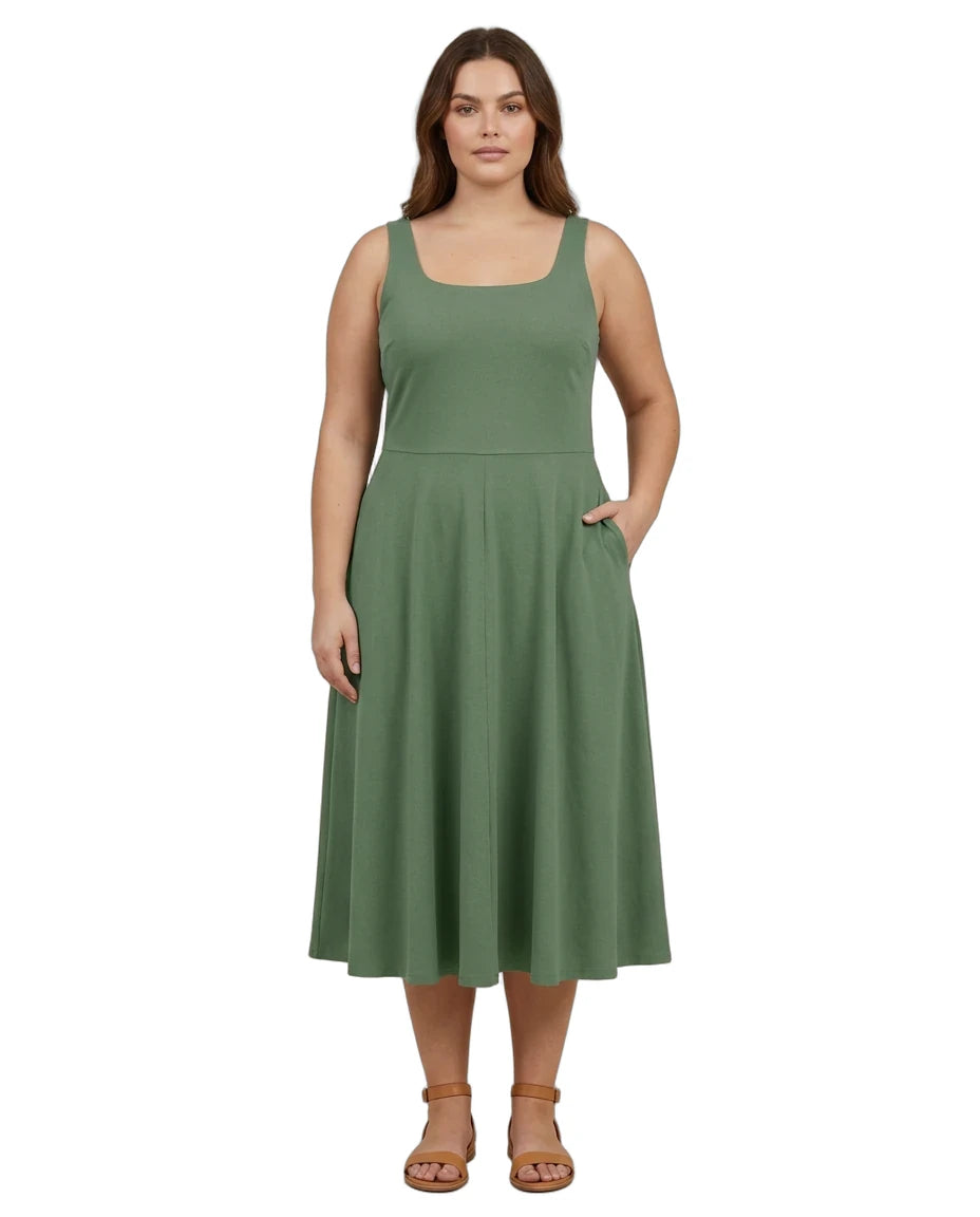 A woman modeling a sleeveless sage green midi dress with a square neckline, fitted waist, and flared skirt with side pockets, paired with tan sandals on a white background.