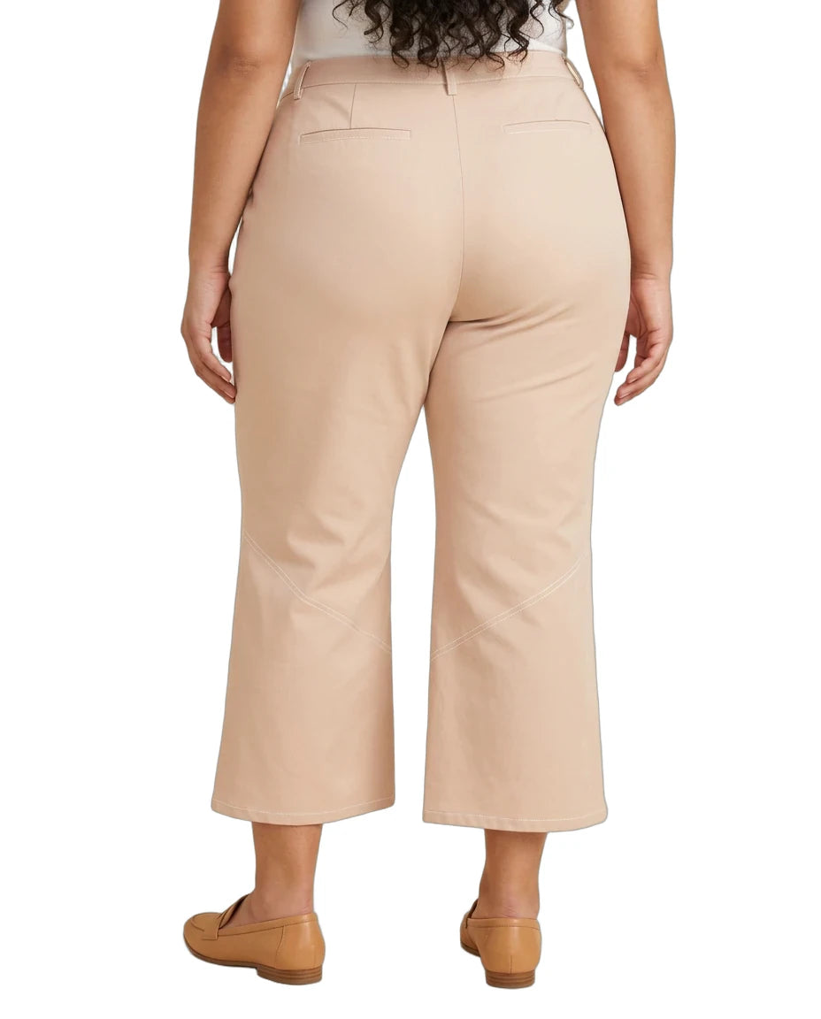 A person shown from the back wearing light beige cropped pants and tan flats against a plain white studio background.