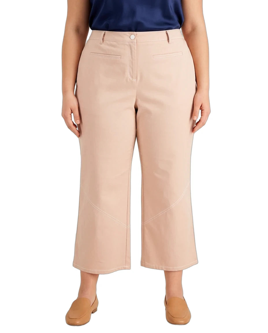 A model wearing a pair of light beige cropped wide-leg pants, paired with a navy top and tan flat shoes, shown against a plain white background.