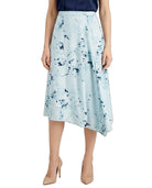 A model wearing a light blue midi skirt with a dark blue abstract floral print, paired with a navy top and beige high heels, shown against a plain white background.