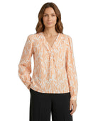 Woman wearing a patterned blouse with long sleeves on a white background