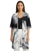Woman wearing a black, white, and gray abstract patterned kimono-style jacket on a white background