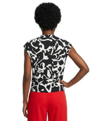 Person wearing a black and white patterned top with red pants on a white background