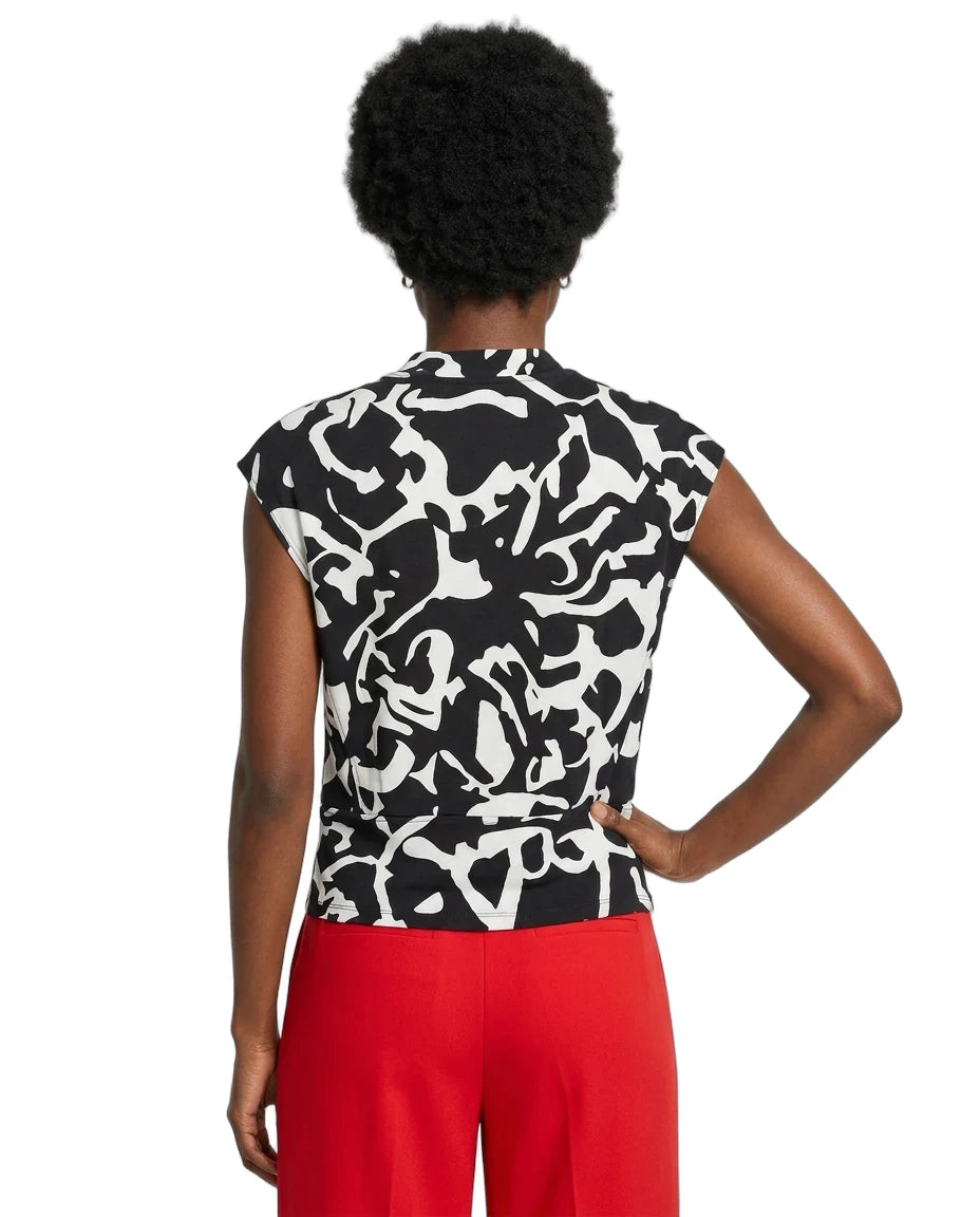 Person wearing a black and white patterned top with red pants on a white background