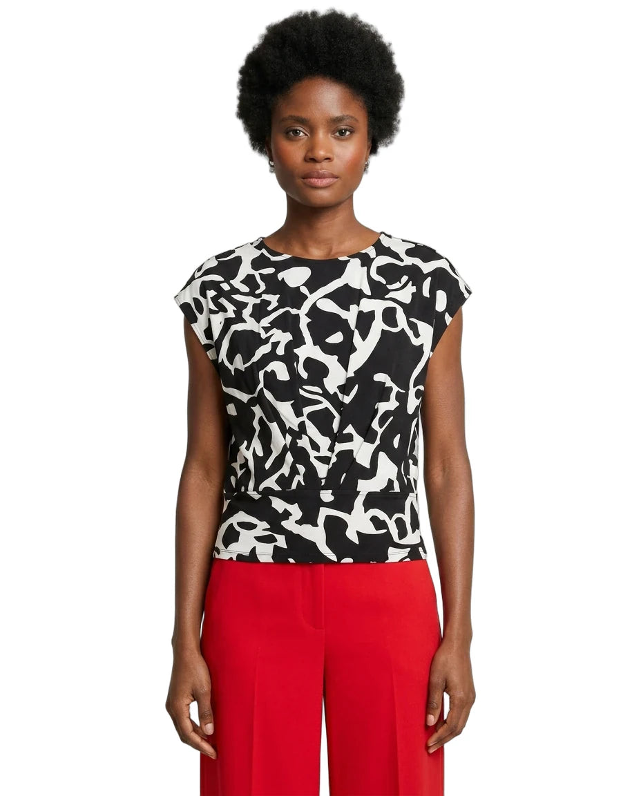 Woman wearing a black and white patterned top with red pants on a white background