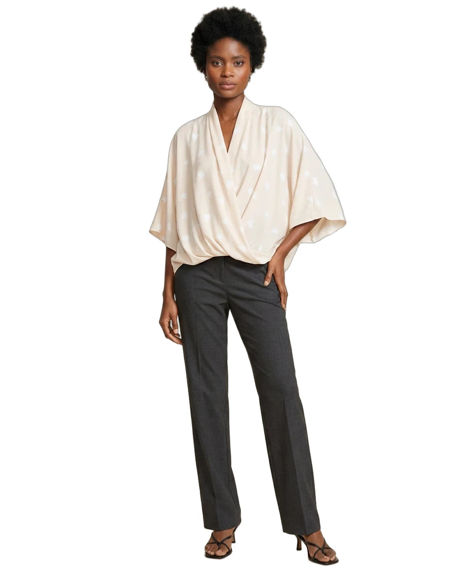 A model wearing a cream-colored, draped short-sleeve top and dark charcoal gray straight-leg trousers, paired with brown strappy heels, against a plain white background.