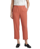 A model wearing a pair of cropped, wide-leg trousers in a muted terracotta or dusty rose color, paired with a white top and black loafers, shown against a plain white background.