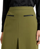 Olive green wide-leg skirt with black leather-like trim on the back pockets, shown on a model wearing a black satin blouse.