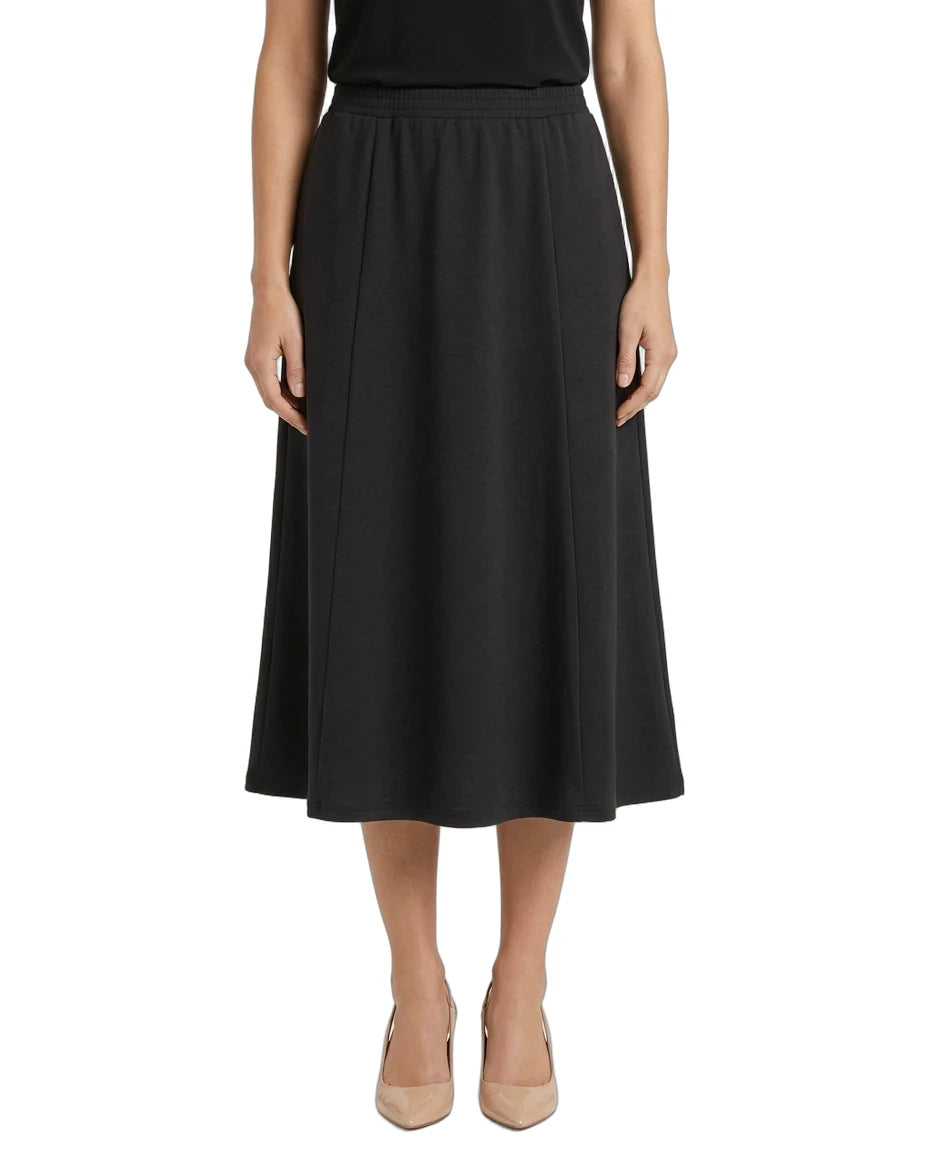 A woman modeling a black midi skirt with a gathered waistband, paired with beige heels, shown against a plain white background.