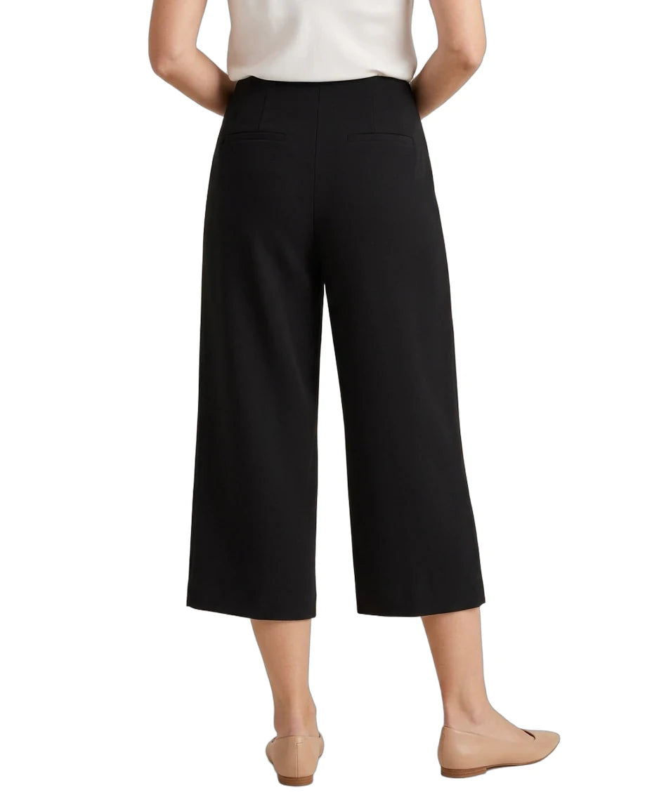 A model shown from the back wearing black cropped wide-leg pants, a white top, and beige flats against a plain white background.