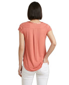Woman wearing a coral-colored t-shirt and white pants on a white background
