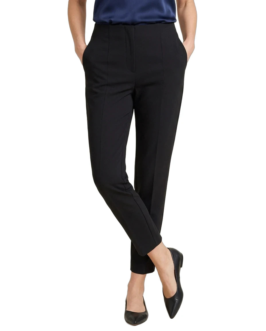 A model wearing black cropped trousers with a navy blue top and black pointed flats, shown from the waist down on a white background.