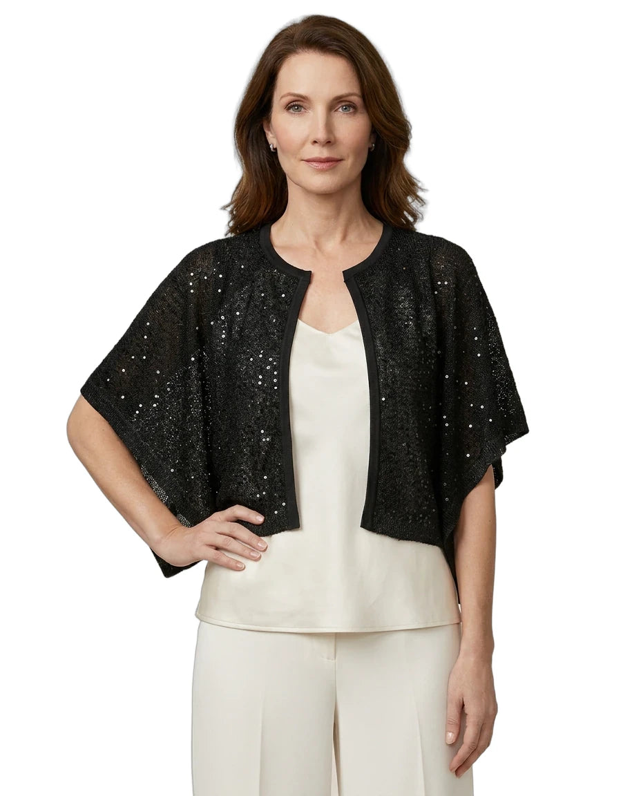 Woman wearing a black sequined jacket over a white top and pants on a white background
