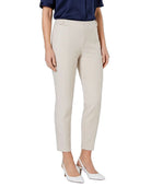 A model wearing a pair of slim-fit, ankle-length cropped trousers in a light beige color, styled with a navy blue top and white pointed-toe heels against a plain white background.