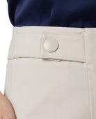 Close-up of a person wearing light beige trousers with a buttoned waistband and a navy top, cropped to show the waist area.