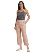 A woman modeling a pair of light blush pink cropped pants with a dark gray satin camisole and white slide sandals, set against a plain white background.