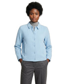 A woman modeling a light blue textured button-up cardigan over a gray turtleneck, paired with gray trousers, against a plain white background.