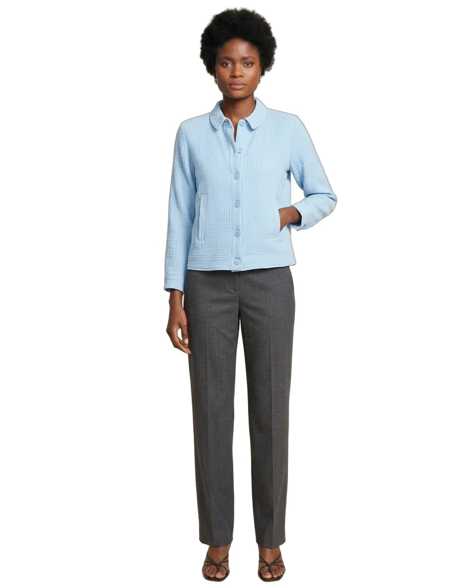 A woman modeling a light blue textured long-sleeve button-up shirt paired with dark gray straight-leg trousers and brown strappy sandals, set against a plain white background.