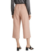 A model is shown from the back wearing high-waisted, cropped wide-leg trousers in a dusty rose pink color, paired with a dark gray long-sleeve shirt and black block-heel slide sandals, against a plain white background.