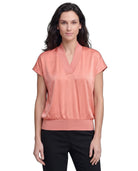 Woman wearing a coral blouse with a white background