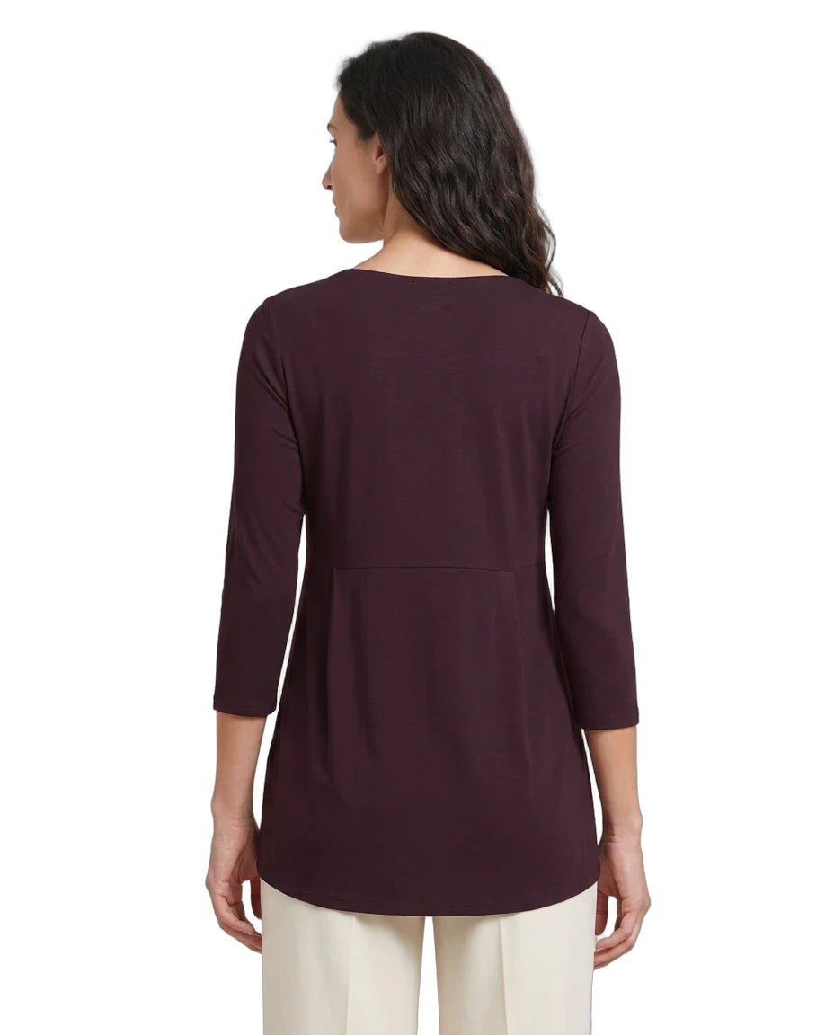 A woman shown from the back wearing a dark plum-colored three-quarter sleeve top and cream pants against a plain white background.