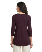 A woman shown from the back wearing a dark plum-colored three-quarter sleeve top and cream pants against a plain white background.