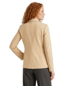 A woman with red curly hair is shown from the back wearing a beige tailored blazer and dark gray trousers against a plain white background.