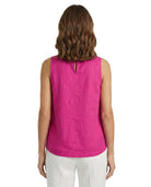 Woman wearing a pink sleeveless top and white pants on a white background