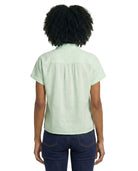 Person wearing a light green shirt and dark blue jeans on a white background