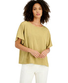Woman wearing a green top and white pants on a white background