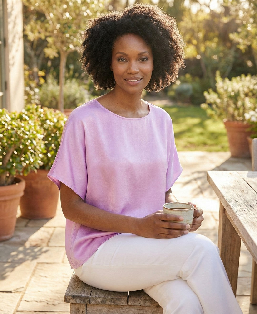 Woman in a pink shirt holding a cup outdoors