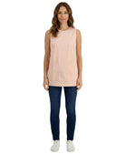 Woman wearing a light pink sleeveless top and dark blue jeans on a white background
