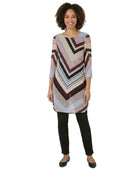 Woman wearing a patterned tunic over black pants on a white background