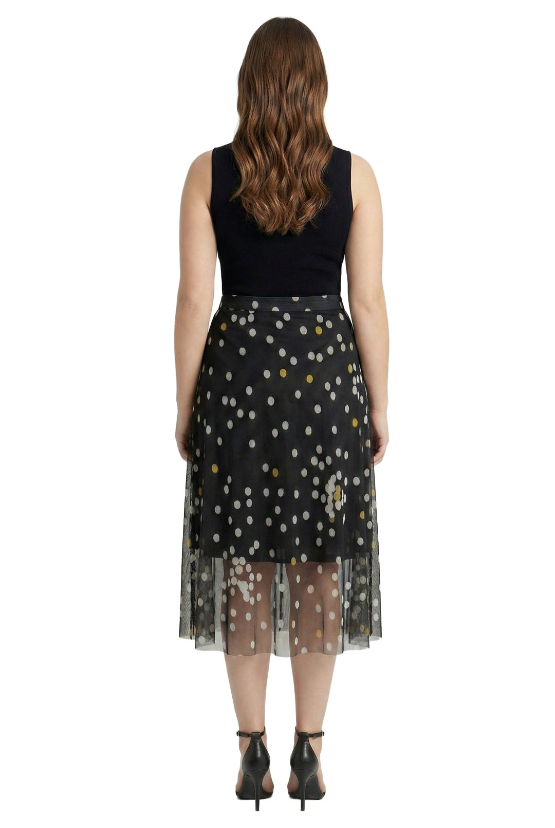 Woman wearing a black sleeveless top and a black skirt with white polka dots on a white background