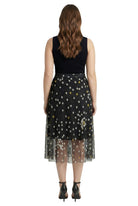 Woman wearing a black sleeveless top and a black skirt with white polka dots on a white background