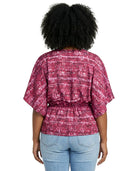 Person wearing a red and white patterned blouse with blue jeans on a white background