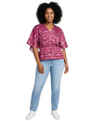 Woman wearing a pink patterned top and light blue jeans on a white background