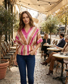 Woman in a colorful striped shirt standing in an outdoor cafe setting