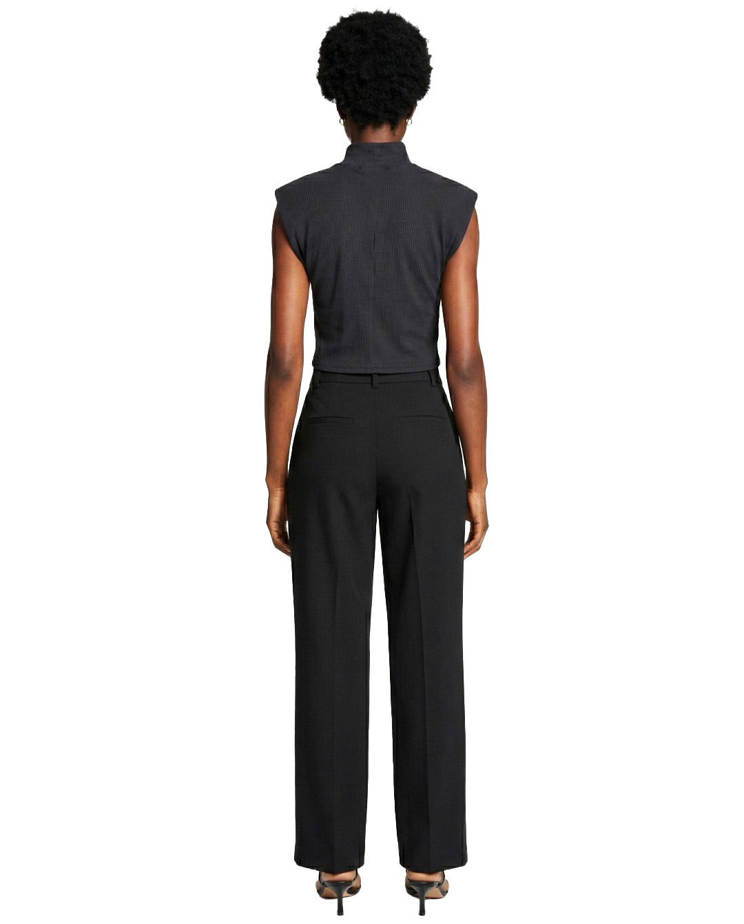 Person wearing a black sleeveless top and black pants on a white background