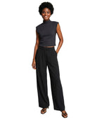 Woman wearing a black sleeveless top and wide-leg pants on a white background