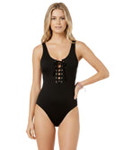 Woman wearing a black one-piece swimsuit with lace-up details on a white background