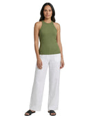 Woman wearing a green sleeveless top and white pants on a white background
