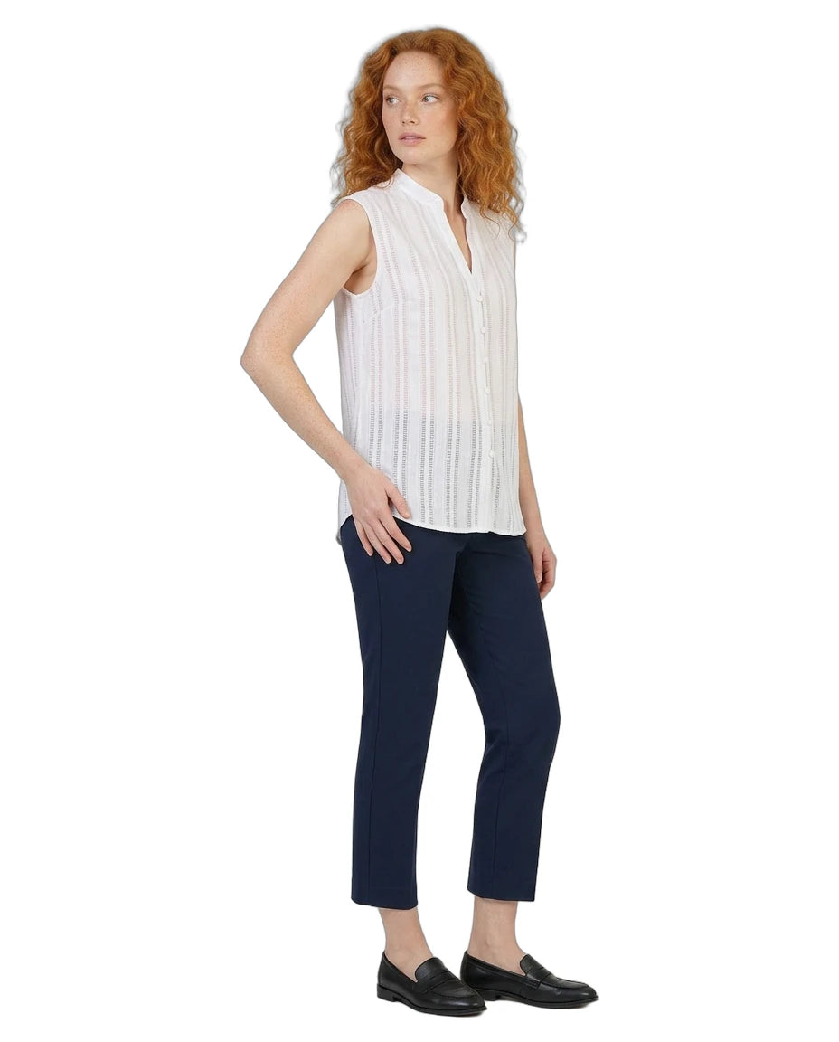Woman wearing a white sleeveless Calvin Klein blouse and navy pants on a white background